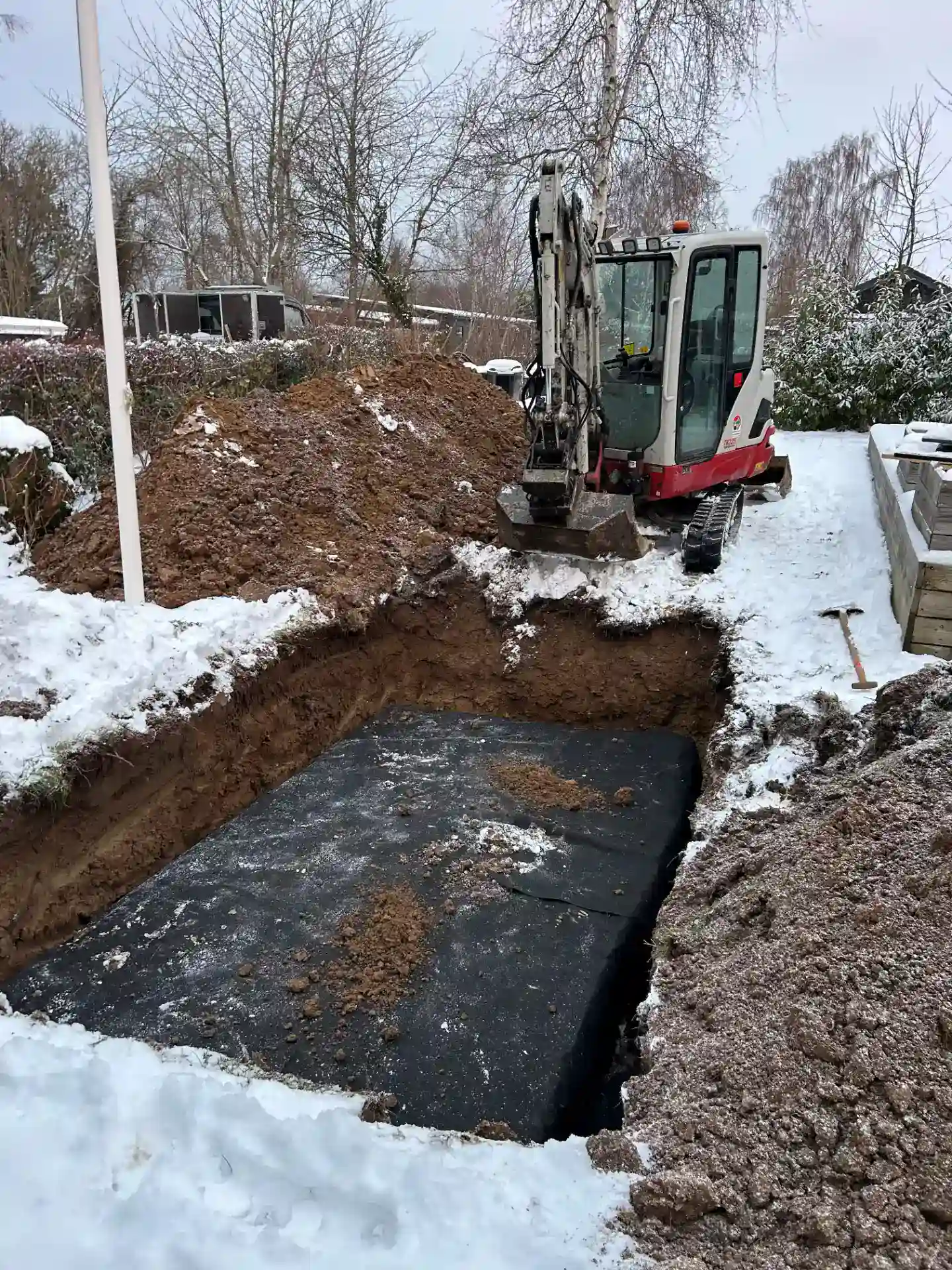 Boring af fundament med minigraver på byggepladsen om vinteren.