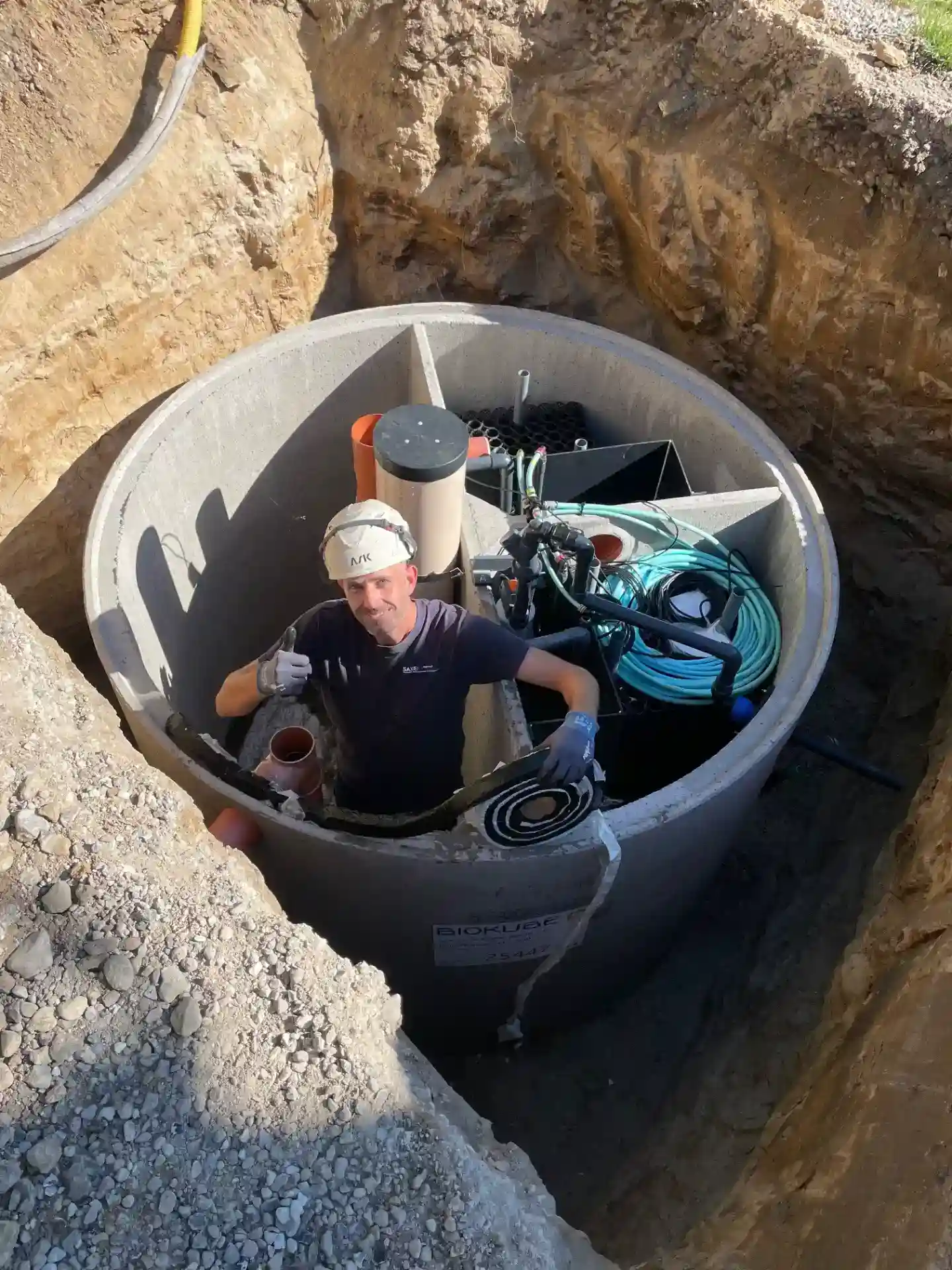 Dykkeren arbejder i en installationsbrønd med vand- og afløbssystemer, klar til vedligeholdelse og inspektion.